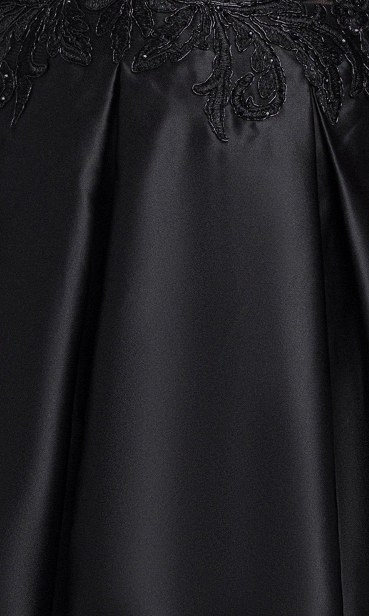 Close-up of smooth black satin fabric with visible pleats and floral embroidery detail at the top edge, highlighting the exquisite craftsmanship of the Plus-Size Black Hoco Dress: Blondie Nites 6346BNW—perfect for your next homecoming event.